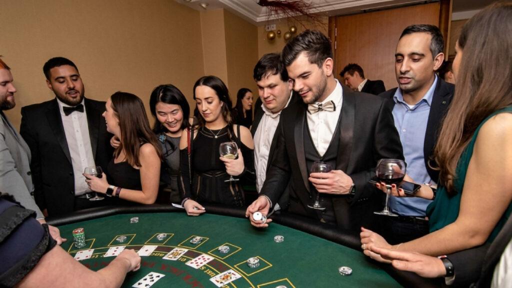 A group of elegantly dressed people in formal wear and black tie standing around a blackjack table, watching a man with a patterned bow tie roll dice on the green felt, capturing the excitement of a high-class Casino Royale.