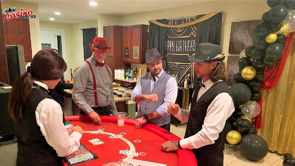 A group of men in Prohibition-era attire—fedoras, vests, and suspenders—playing at a bright red blackjack table during a themed casino event.